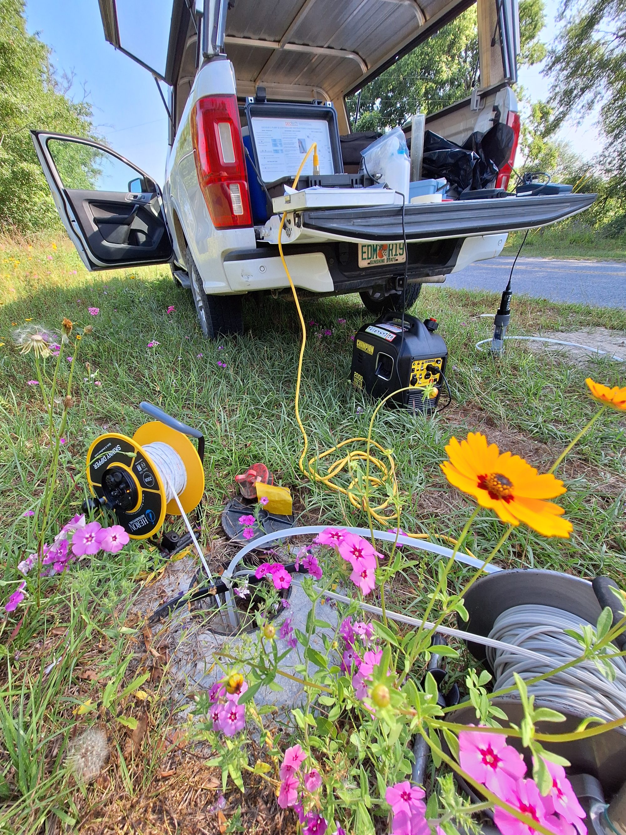 Photo of groundwater sampling equipment with pink and yellow flowers in the foreground