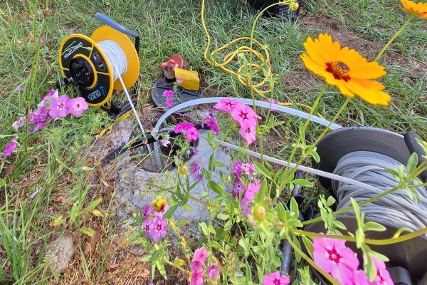 Photo of groundwater sampling equipment with pink and yellow flowers in the foreground