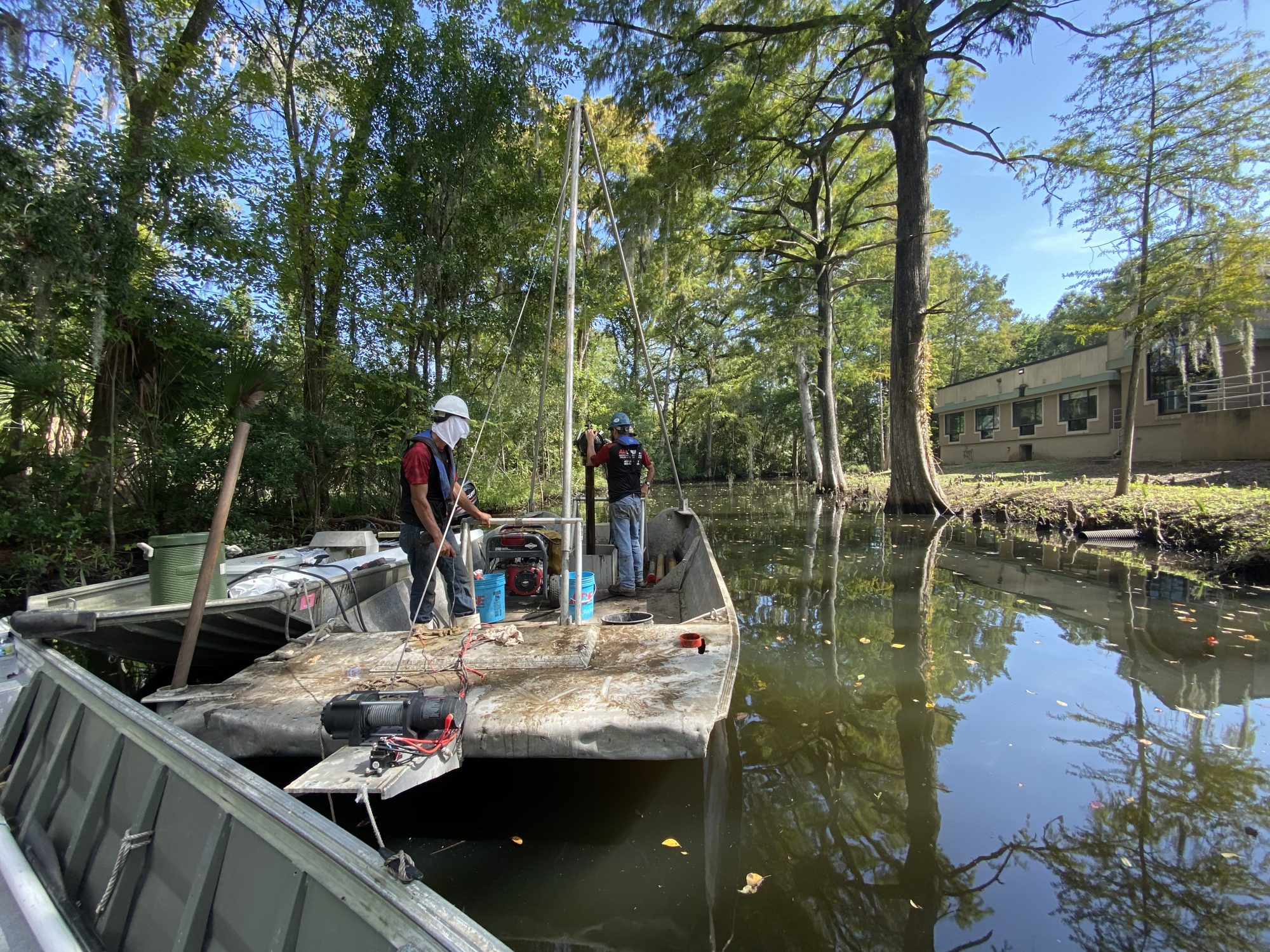 photo of a crew using a vibracore to collect a core sample from a boat
