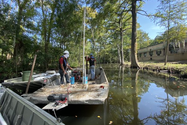 photo of a crew using a vibracore to collect a core sample from a boat